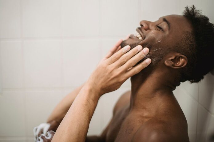 skincare-routine-homme-type-peau-age A close-up portrait of a happy man enjoying a refreshing shower, embodying relaxation and self-care.