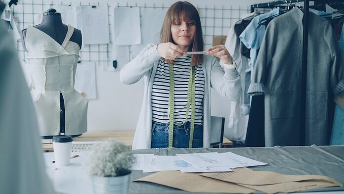 A fashion designer measures with a tape measure.