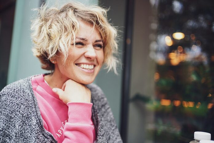 coiffure-tendance-femme-50-ans-coupes-courtes-mi-longues-affiner-visage-rond smiling girl in pink shirt and gray cardigan
